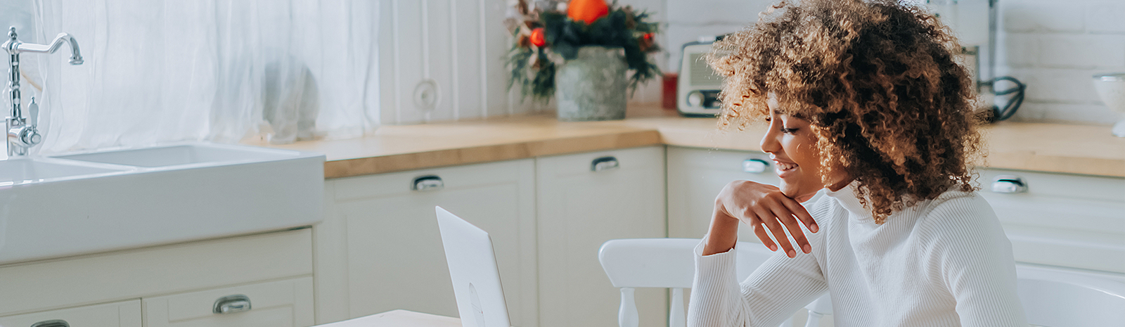 woman sitting in kitchen looking at her computer